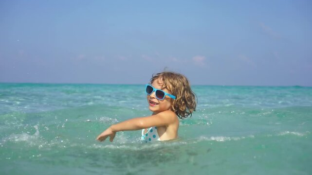 A happy child is having fun in the sea during the summer holidays. Slow motion