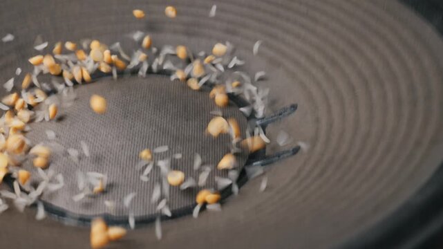 Yellow split peas and rice grains bounce on a vibrating black loudspeaker cone during a physics test. Concept of sound waves, cymatics, frequency visualization, and audio energy.