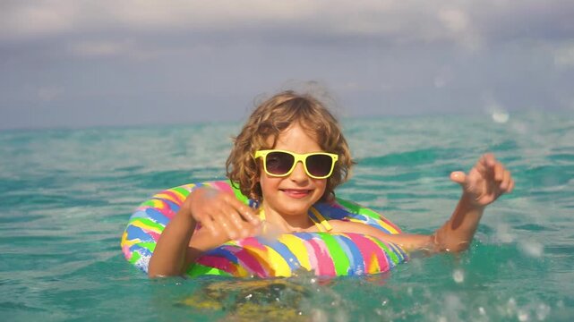 A happy child is having fun in the sea during the summer holidays. Slow motion