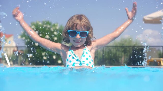 A happy child is having fun in the swimming pool during the summer holidays. Slow motion