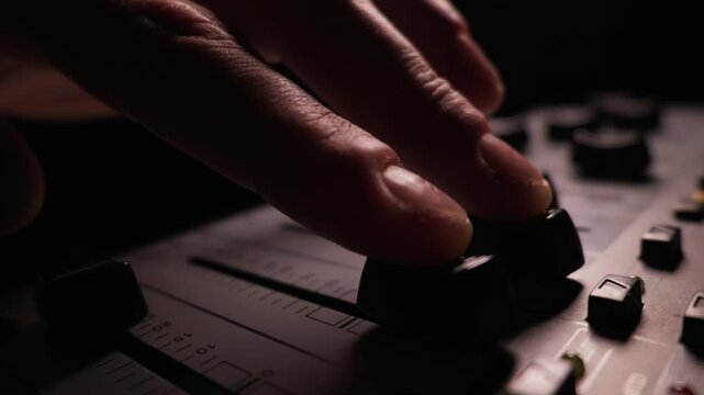 Blurred finger slides a volume fader up on a professional audio mixing console with extreme macro focus. Concept of modern music production, live sound engineering and precise audio control.