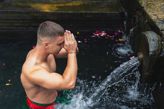 Young man praying in sacred water pool