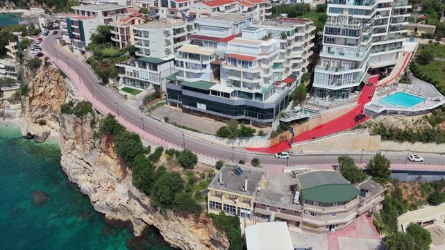 Aerial view of Vlora's  clifftop developments, winding coastal road and turquoise Ionian sea
