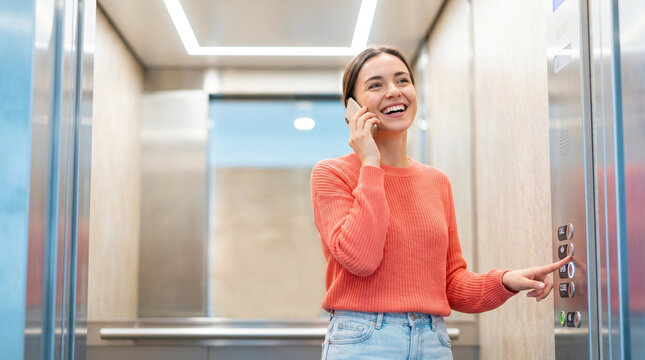 Young woman smiling while talking on phone in elevator  