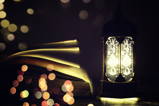Ramadan Kareem background. Ornamental Arabic lantern glowing and the holy book of Quran.