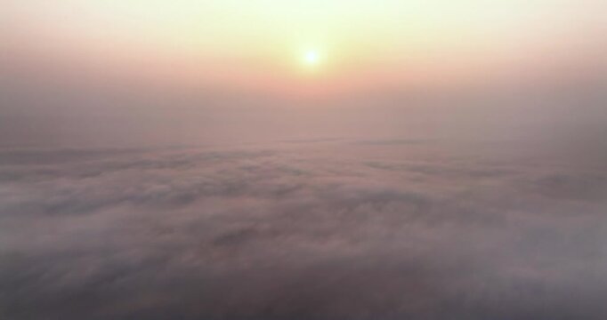 Aerial view of the sun shining through a thick layer of morning fog and clouds at dawn in Kurigram, Rangpur Division, Bangladesh.