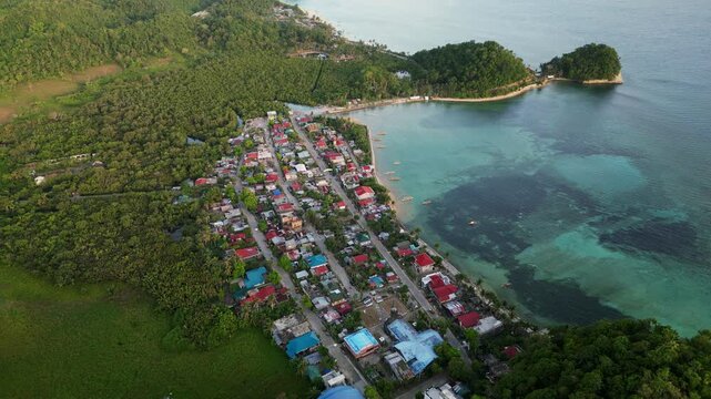 Rising aerial view of a lush fishing village along the tropical coastline of Catanduanes, Bicol, Philippines