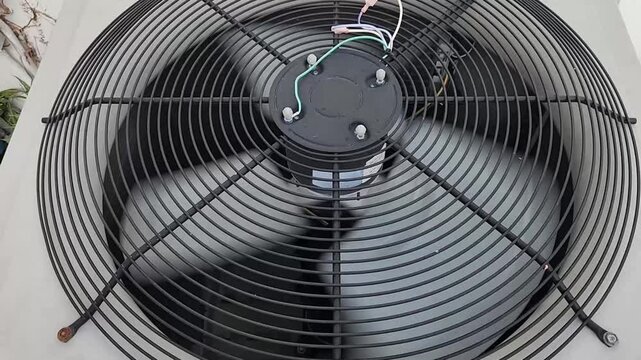 Top view of rotating fan inside outdoor HVAC condenser unit