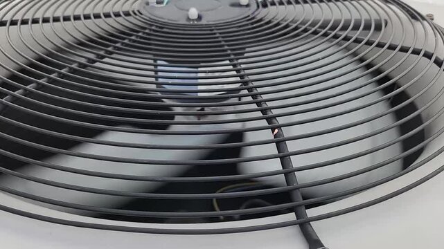 Detailed video clip of a rotating fan inside an outdoor air conditioning condenser unit. Cooling and ventilation equipment operating during residential climate control.