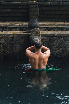 Man praying in a temple pool