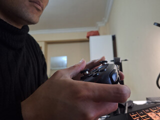 Young man holds game controller with focused expression © Abdan Zaki