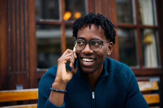 Young African American man enjoying in conversation over cell phone outdoors.