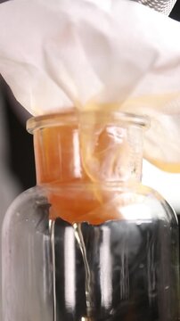 Chef filtrando l&iacute;quido infusionado en c&aacute;mara lenta (primer plano). Un chef profesional colando l&iacute;quido infusionado en c&aacute;mara lenta. Proceso culinario cinematogr&aacute;fico, gastronom&iacute;a moderna.