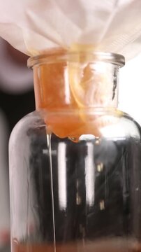 Chef filtrando l&iacute;quido infusionado en c&aacute;mara lenta (primer plano). Un chef profesional colando l&iacute;quido infusionado en c&aacute;mara lenta. Proceso culinario cinematogr&aacute;fico, gastronom&iacute;a moderna.