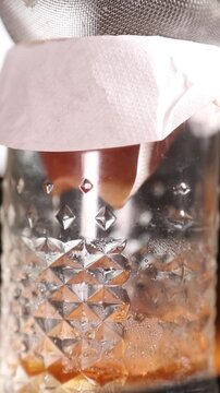 Chef filtrando l&iacute;quido infusionado en c&aacute;mara lenta (primer plano). Un chef profesional colando l&iacute;quido infusionado en c&aacute;mara lenta. Proceso culinario cinematogr&aacute;fico, gastronom&iacute;a moderna.