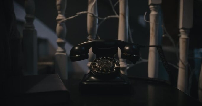 Rotary phone ringing as woman points flashlight at it and hesitates to pick it up in haunted, hazy house - closeup