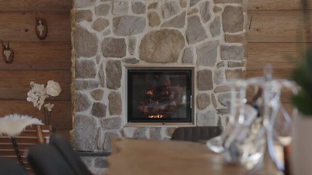 Warm, crackling fire burning in a stone fireplace inside a rustic wooden chalet interior