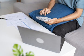Fototapeta premium Man Managing Personal Finances Budget Household Expenses and Calculating Taxes with Calculator on the Table at Home.