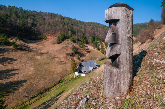 View of a wooden totem carving overlooking a traditional cottage in the valley of the Prasnica old charcoal burners settlement Stare Hory, Banskobystricky kraj, Slovakia.