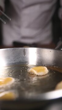 Chef friendo pani puri en sart&eacute;n de acero inoxidable (primer plano). Un chef profesional fr&iacute;e pani puri crujiente en una sart&eacute;n de acero. Comida callejera india, receta tradicional.