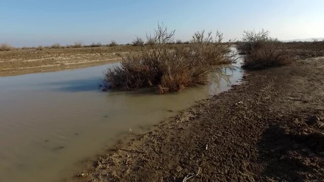 Dry riverbed with scattered rocks in arid landscape creating geological and nature documentary scene perfect for travel stock video footage.