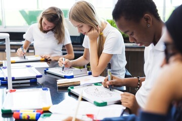 Fototapeta premium Students focused on drawing in a classroom setting.
