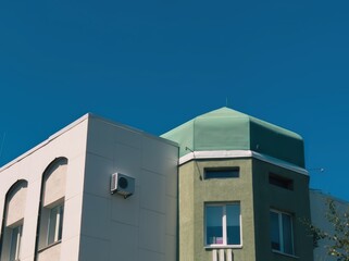Obraz premium Modern architectural design of green building with rooftop against clear blue sky