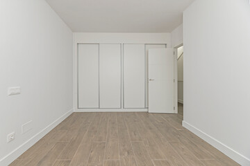Fototapeta premium An open and immaculate space where the only elements are built-in wardrobes with mirrored doors, visually doubling the feeling of spaciousness.