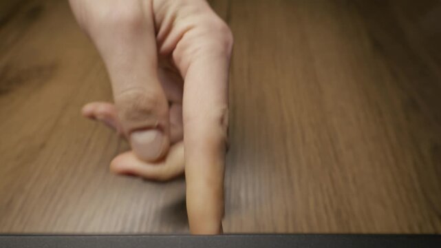 A male hand inserts a black VHS cassette into a vintage player recorder on a wooden table. Concept of retro technology, watching home movies, and nostalgic entertainment from the nineties.