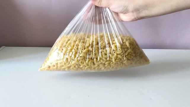 A woman's hand puts a bag of durum pasta on the table.