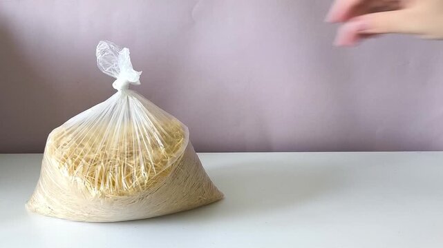 A woman's hand puts a bag of durum pasta on the table.