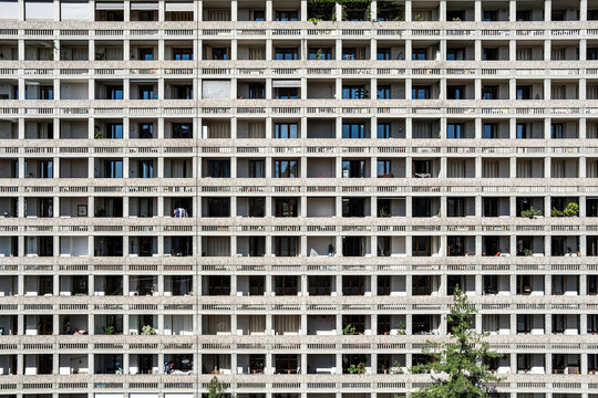 Apartments fill an urban residential building facade, where balconies and windows create a dense grid pattern across repetitive architecture