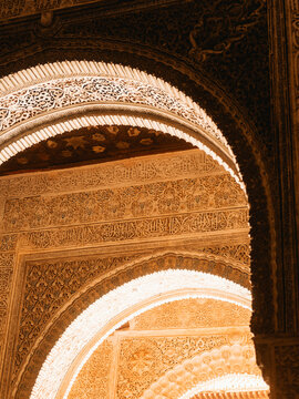 View of the intricate stucco carvings and calligraphic details on the arches of the Alhambra palace in Granada, Andalusia, Spain.