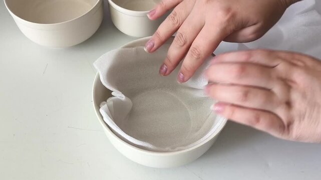 A woman packs dishes for moving. Female hands placing polyethylene foam between ceramic cups