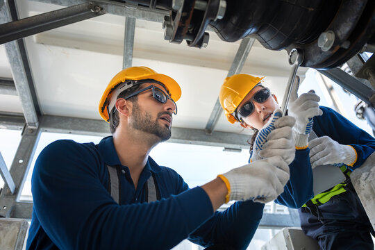 Industrial technicians team working together on pipe plumbing, Workers inspecting heavy-duty cooling equipment and valves, Engineers collaborating on industrial HVAC system pipework maintenance