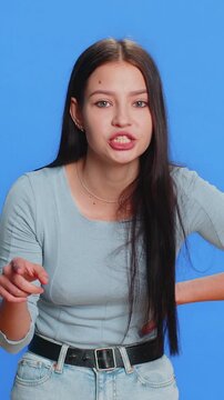Quarrel. Displeased aggressive unhappy Caucasian young woman gesturing hands with irritation and displeasure, blaming scolding for failure, asking why this happened. Girl isolated on blue background