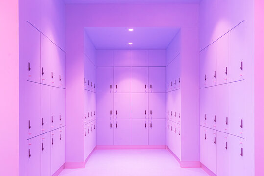 A perfectly symmetrical interior photograph of a modern, minimalist locker room corridor. The walls are lined with sleek, built-in storage cabinets finished in a uniform light sky blue color, each 