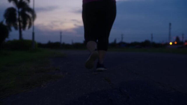 Low-angle view of a middle-aged woman running outdoors at nightfall