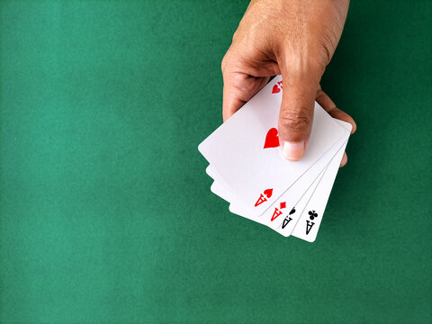Close-up of a hand holding full set of four aces over a green table.