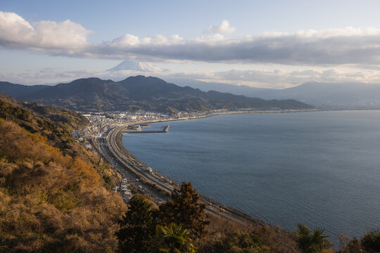 View of the iconic Mount Fuji rising above Suruga Bay and the coastal highway from the Satta Pass Observation Deck in Shizuoka, Shizuoka, Japan.