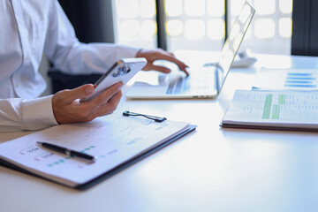 Fototapeta premium Professional businessman, entrepreneur or accountant working on a financial report paperwork at his desk, using mobile phone.