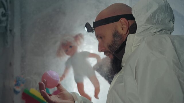 Bearded caucasian scientist holding frozen doll inside protective suit, headlamp beam illuminating ice crystals and dust in abandoned frostcovered house, tense postapocalyptic atmosphere, hints