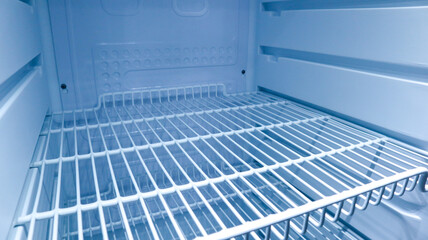 Fototapeta premium Interior view of an empty clean refrigerator looking slightly to the right side of wire shelves