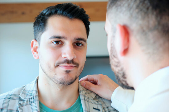 Portrait of young adult Caucasian man receiving shoulder support from another man, suggesting trust and reassurance. Useful for counseling, teamwork, mentorship, mental health campaigns