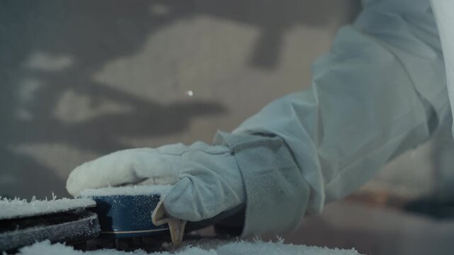 Gloved hand holding sensor device bearded researcher in protective suit examines frostcovered instrument under lamp beam breath visible in cold air methodical inspection by field technician engineer