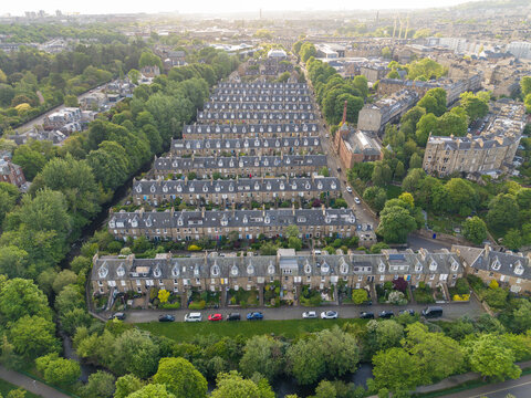 Aerial view of the historic stone buildings of Well Court in Dean Village surrounded by lush green trees and the Water of Leith in Edinburgh, Scotland, United Kingdom.