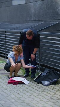 Business partners review scattered documents on the pavement, facing an unexpected project setback. Colleagues collaborate to assess and overcome a difficult situation outdoors.