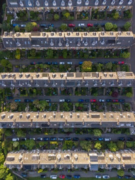 Aerial view of traditional terraced houses with grey slate roofs, dormer windows, and private gardens in Edinburgh, Scotland, United Kingdom.