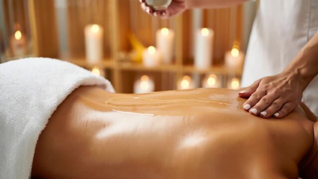 Relaxing Body Massage with Aromatic Oil and Blurred Burning Candles Background