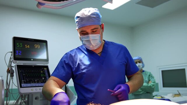 Neurosurgeon in blue scrubs concentrating at operating table with monitors displaying vitals. Male surgeon in cap and mask, patient monitor with vital signs and nurse in background.